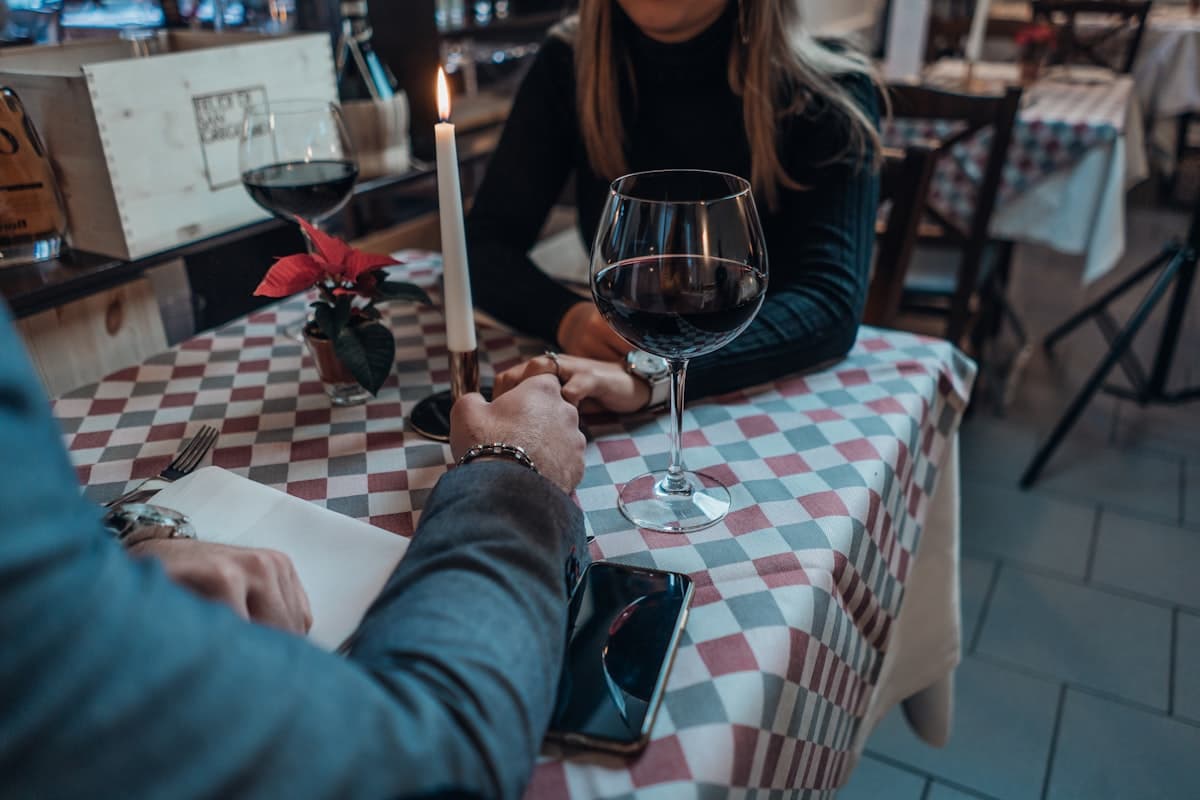 A couple holding hands over a candlelit dinner table